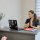 Woman working on a laptop at a desk.