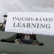 a close up of a typewriter with an inquiry - based learning sign