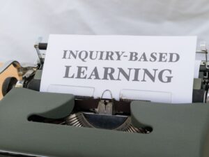 a close up of a typewriter with an inquiry - based learning sign