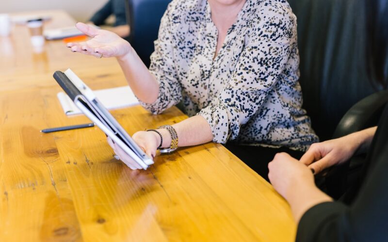 woman holding tablet computer showing to seatmate