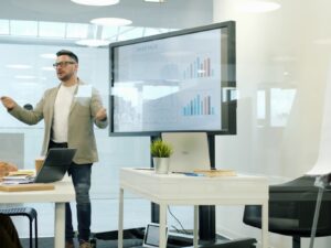 Man presenting data on a large screen to colleagues.