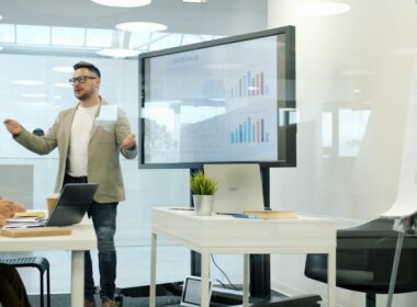 Man presenting data on a large screen to colleagues.