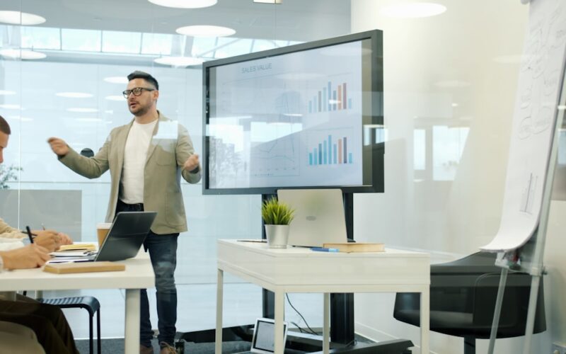Man presenting data on a large screen to colleagues.