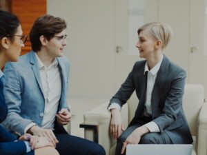 Three professionals in business attire conversing indoors.