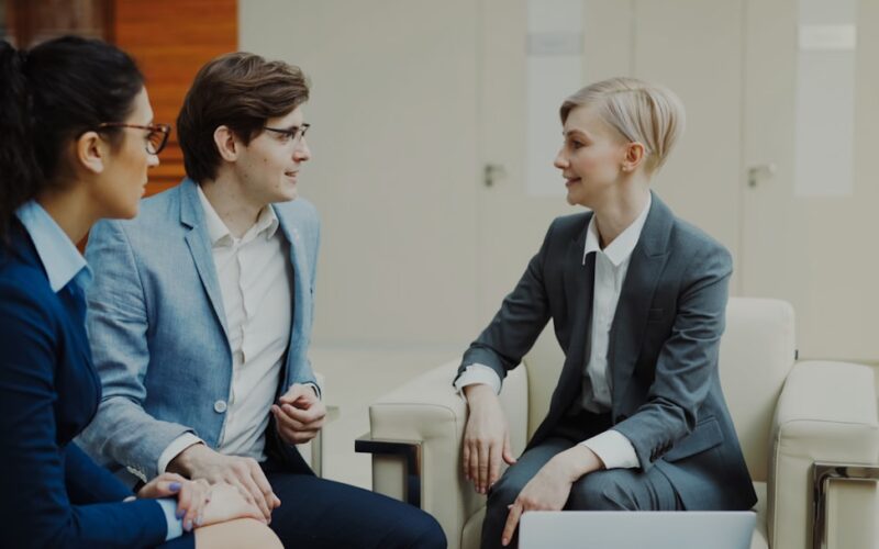 Three professionals in business attire conversing indoors.