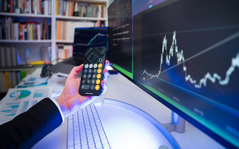 A man holding a remote control in front of a computer