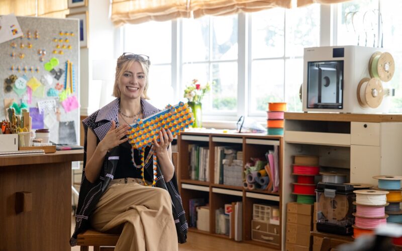 Woman holding colorful beaded necklace in workshop