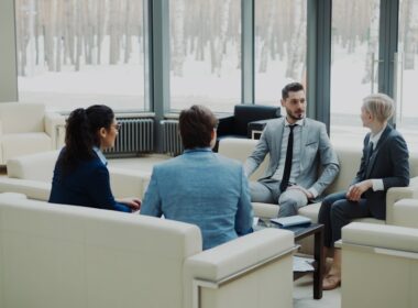 Four professionals in a modern office meeting space.