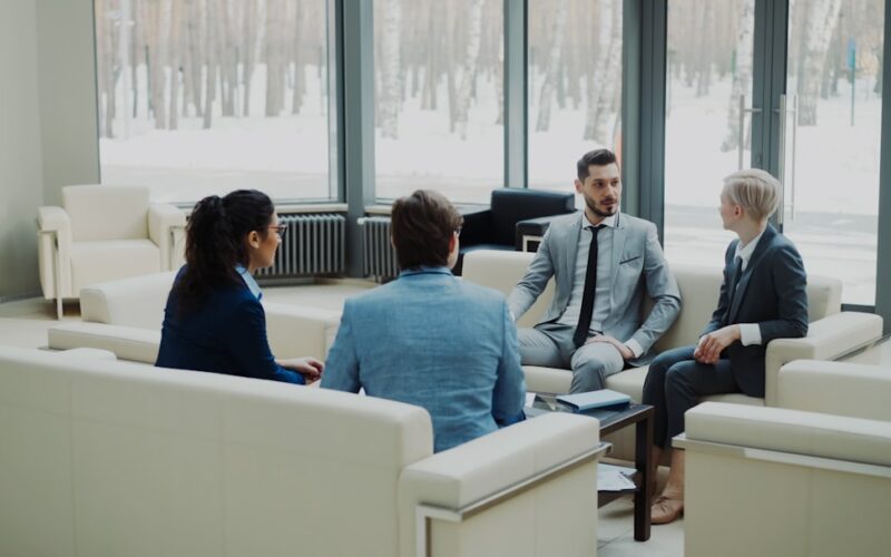Four professionals in a modern office meeting space.
