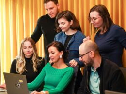 a group of people sitting around a laptop computer