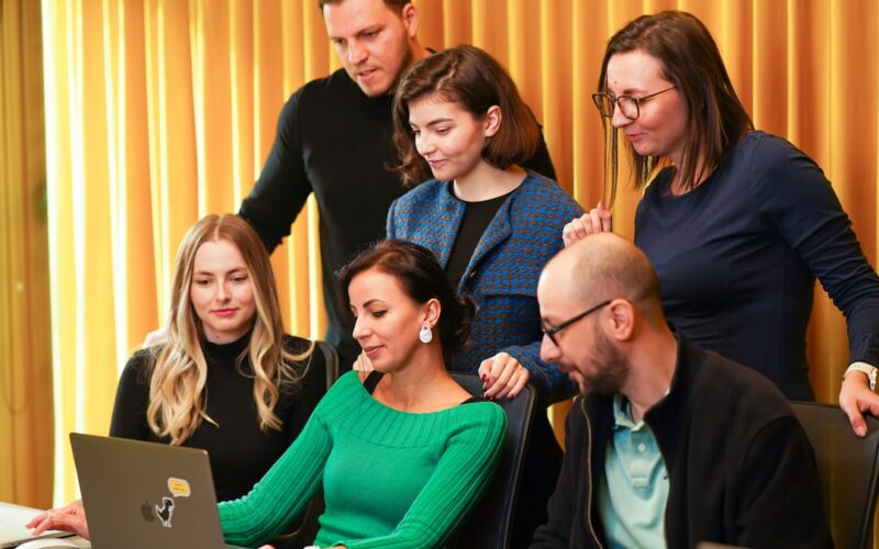a group of people sitting around a laptop computer