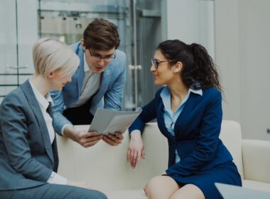 Three business people in suits discussing documents.