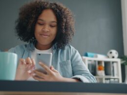 Young girl using a smartphone at a desk.