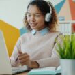 Young woman wearing headphones works on laptop.
