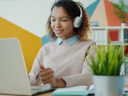 Young woman wearing headphones works on laptop.