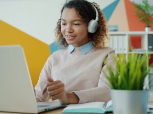 Young woman wearing headphones works on laptop.