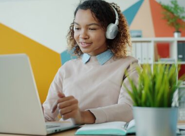 Young woman wearing headphones works on laptop.