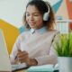 Young woman wearing headphones works on laptop.