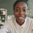 Young woman smiles at the camera in an office setting.