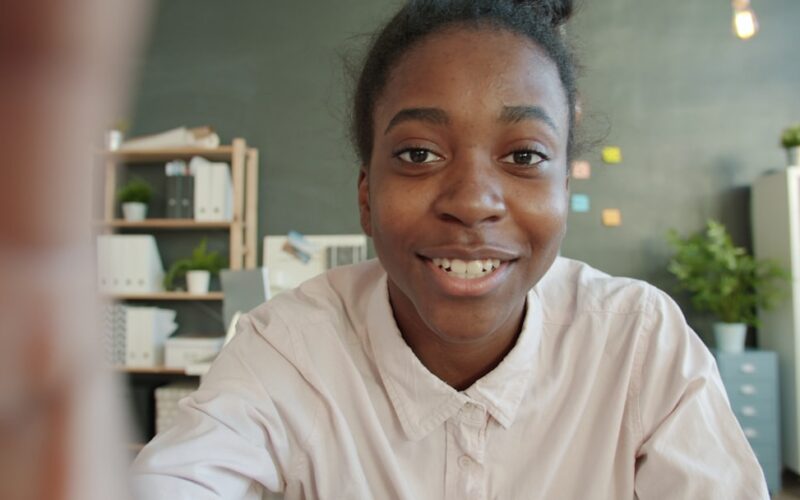 Young woman smiles at the camera in an office setting.