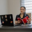 Woman reading a book at an office desk.