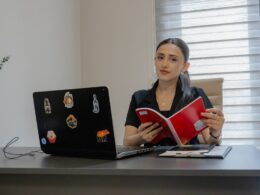 Woman reading a book at an office desk.
