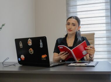 Woman reading a book at an office desk.