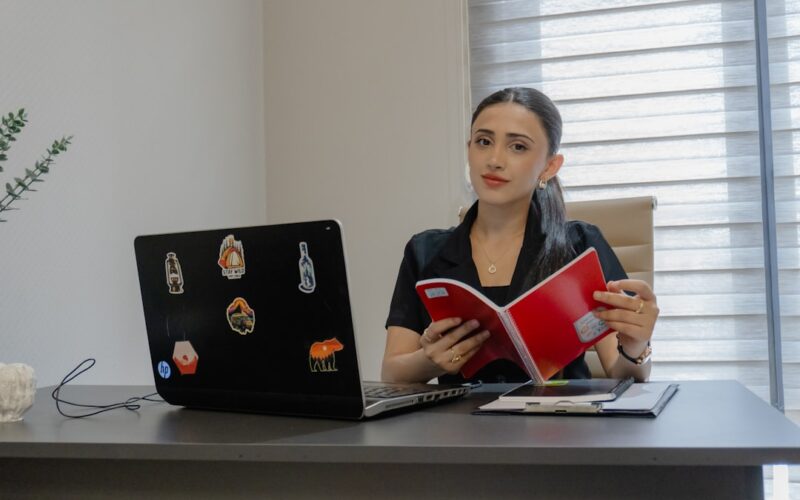 Woman reading a book at an office desk.