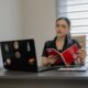 Woman reading a book at an office desk.