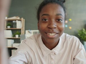 Young woman smiles at the camera in an office setting.