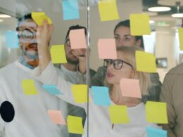 Team brainstorming with sticky notes on glass wall.