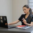 A woman working on a laptop at a desk.