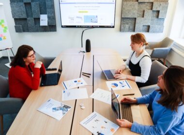 a group of women sitting around a table working on laptops
