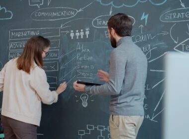 Two people collaborating on a chalkboard with diagrams.