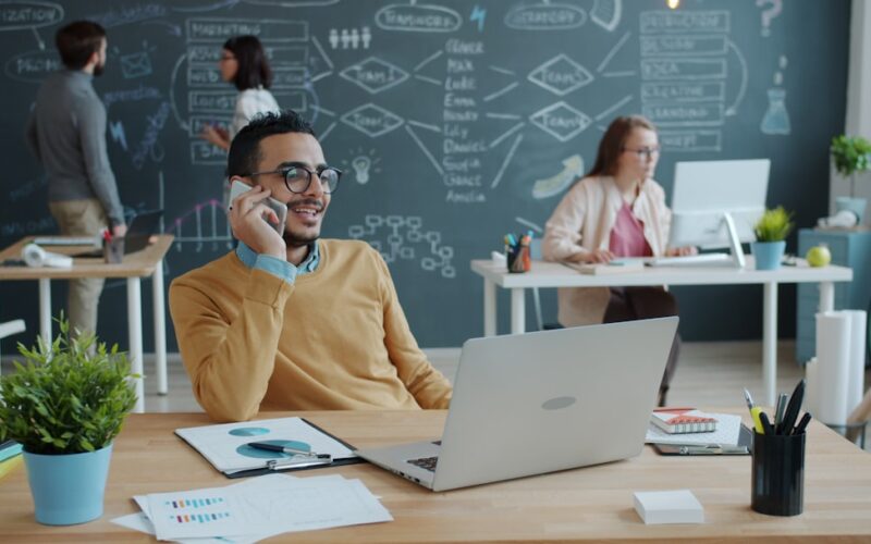 Man talking on phone in modern office with team