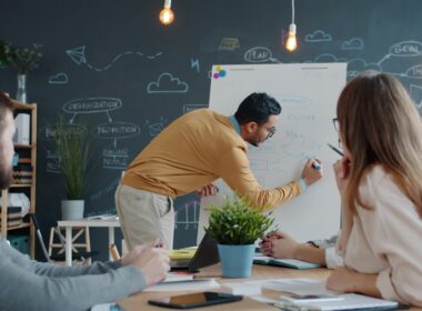 Man presenting ideas on whiteboard to colleagues