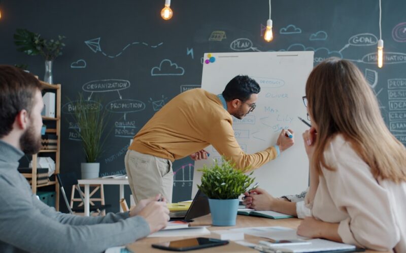 Man presenting ideas on whiteboard to colleagues