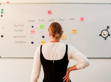 a woman standing in front of a white board with sticky notes on it